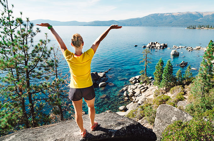 woman standing on a rock looking out over lake tahoe